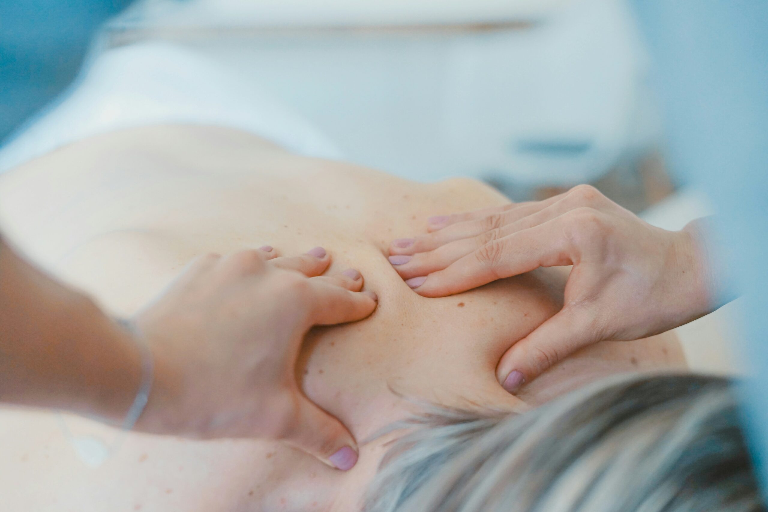 Worker massaging client on bed